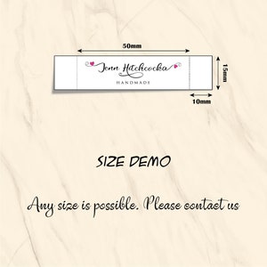 Puede incluir: Una etiqueta blanca con corazones rosas y el texto "Jenn Hitchcocka HANDMADE" en letra cursiva negra. La etiqueta mide 50 mm de ancho por 15 mm de alto. El texto "SIZE DEMO" est&aacute; escrito debajo de la etiqueta. El texto "Any size is possible. Please contact us" est&aacute; escrito debajo del texto "SIZE DEMO".