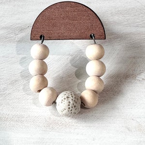 May include: A wooden half-circle with two holes and a string of wooden beads with a textured white bead in the center.