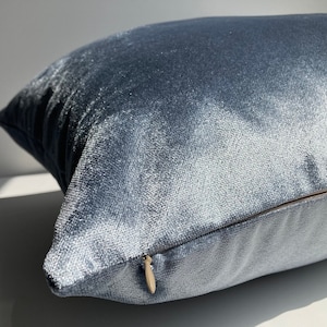 May include: A soft, blue velvet pillow with a zipper closure. The pillow is made of a luxurious fabric and has a subtle sheen.