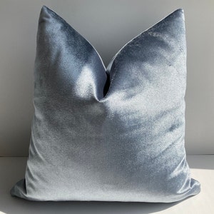 May include: A soft, light blue velvet pillow cover. The pillow is square and has a smooth, luxurious texture.
