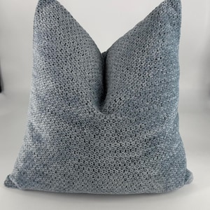 May include: A gray, textured throw pillow with a square shape. The pillow is made of a soft, woven fabric.