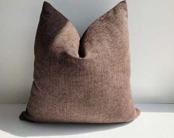 May include: A brown throw pillow with a textured fabric. The pillow is square shaped and has a simple design.