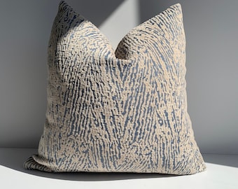 May include: A decorative throw pillow with a blue and cream abstract pattern. The pillow is made of a textured fabric and has a square shape.