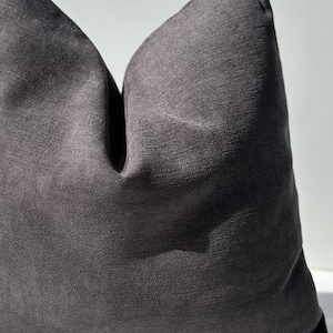 May include: A dark gray throw pillow with a textured fabric. The pillow is folded in half and the fabric has a subtle sheen.