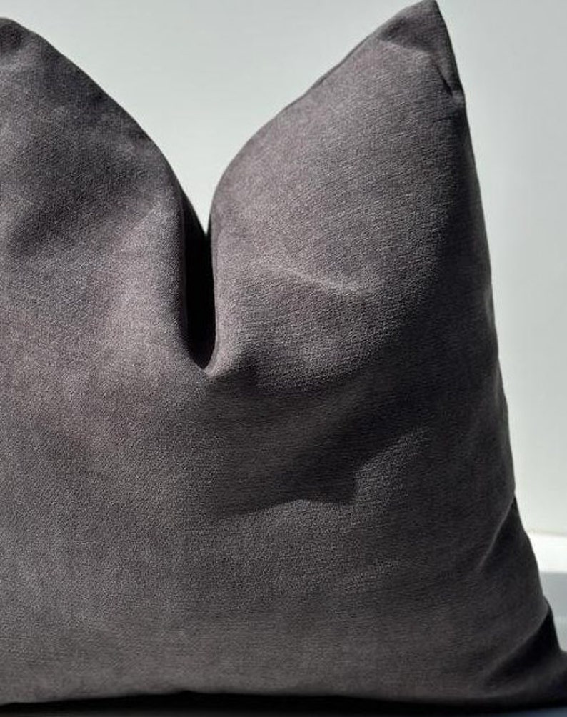 May include: A dark gray throw pillow with a textured fabric. The pillow is folded in half and the fabric has a subtle sheen.