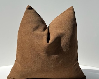 May include: A brown throw pillow with a textured fabric. The pillow is square shaped and has a simple design.
