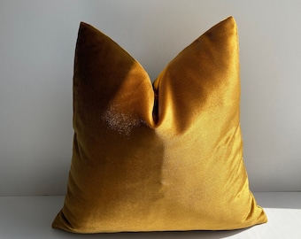 May include: A soft, plush velvet pillow in a rich mustard yellow color. The pillow is square shaped and has a simple, elegant design.