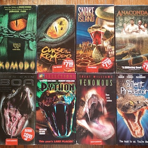 May include: A collection of VHS tapes featuring snake and reptile-themed horror movies. The titles include "Komodo", "Curse of the Komodo", "Snake Island", "Anacondas", "Boa", "Python", "Venomous", and "Silent Predators".