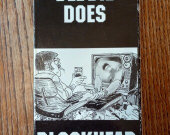May include: A vintage VHS tape with the title "DEBBIE DOES BLOCKHEAD" in bold white letters on a black background. The cover features a black and white illustration of a man watching TV and drinking beer.