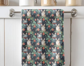 May include: A decorative kitchen towel featuring a repeating pattern of watercolor cats wearing festive collars, surrounded by Christmas ornaments and evergreen branches on a dark background. The towel is hanging on a silver bar.