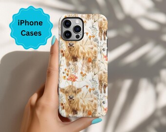 May include: A white iPhone case with a watercolor design of Highland cows and wildflowers. The case has a black camera bump and a white background.