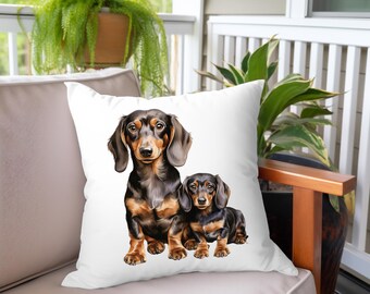 May include: A white throw pillow with a printed image of two black and tan dachshund dogs. The larger dachshund is sitting with its paws crossed, while the smaller dachshund is sitting with its head tilted to the side.