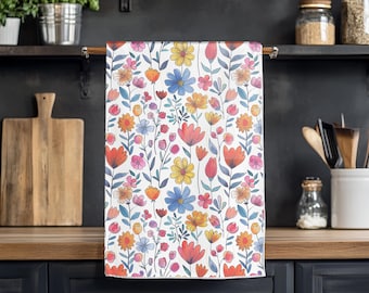 May include: A white kitchen towel with a colorful floral pattern. The pattern features pink, red, yellow, blue, and green flowers on a white background.