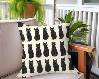 May include: A white throw pillow with a repeating pattern of black cats. The cats are all facing forward with their tails curled around their legs.