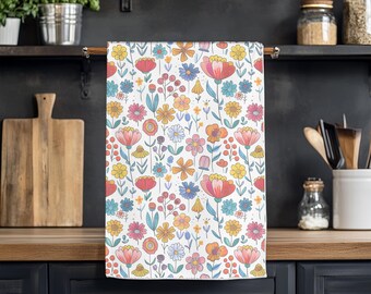 May include: A white kitchen towel with a colorful floral pattern. The pattern features pink, red, yellow, blue, and green flowers on a white background.