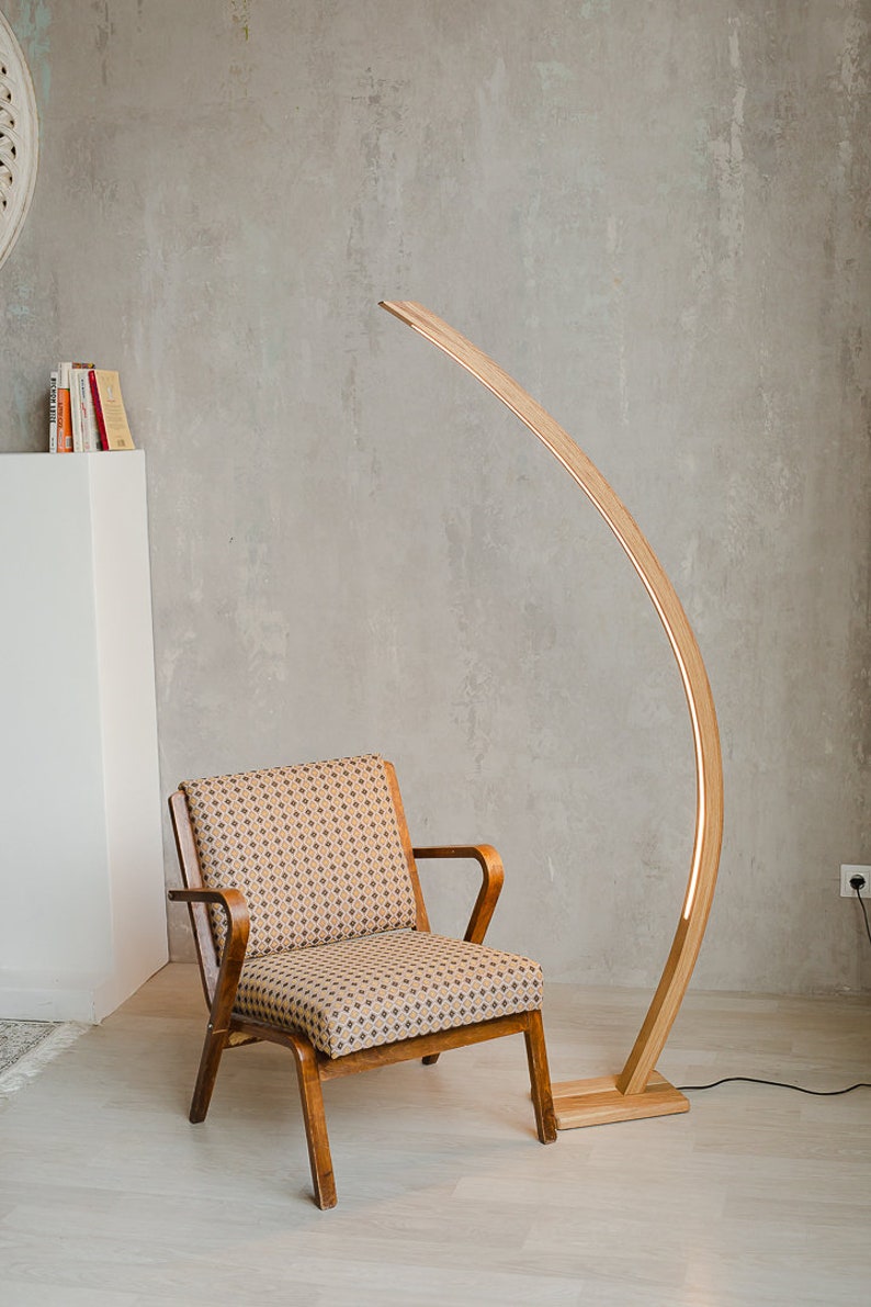 Curved wooden floor lamp with remote control, to adjust the brightness, you can also choose the temperature of the glow warm or neutral. The handmade LED floor lamp is made of solid oak, the tree can be tinted in 10 colors to choose from