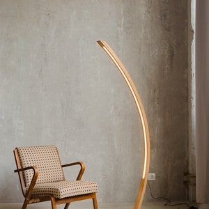 Curved wooden floor lamp with remote control, to adjust the brightness, you can also choose the temperature of the glow warm or neutral. The handmade LED floor lamp is made of solid oak, the tree can be tinted in 10 colors to choose from