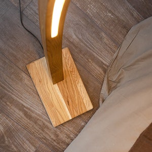 Curved wooden floor lamp with remote control, to adjust the brightness, you can also choose the temperature of the glow warm or neutral. The handmade LED floor lamp is made of solid oak, the tree can be tinted in 10 colors to choose from