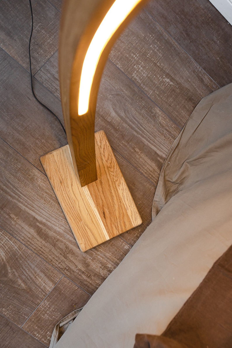 Curved wooden floor lamp with remote control, to adjust the brightness, you can also choose the temperature of the glow warm or neutral. The handmade LED floor lamp is made of solid oak, the tree can be tinted in 10 colors to choose from