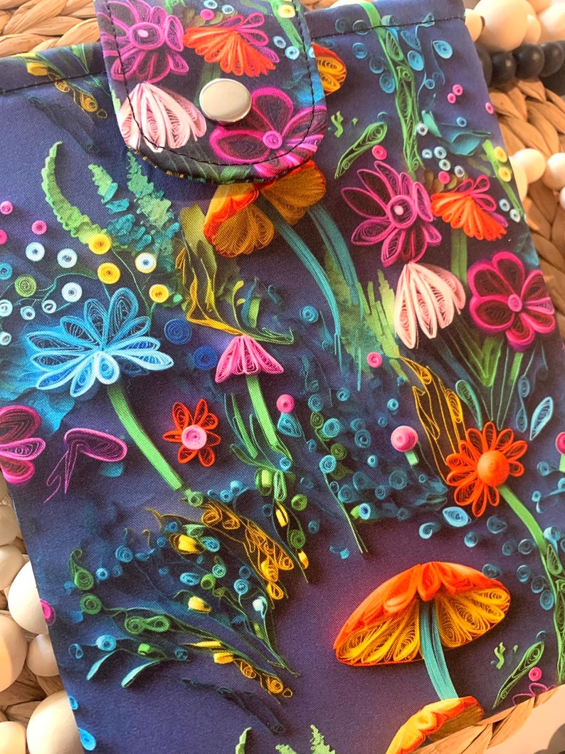 May include: A dark blue fabric pouch with a colorful floral design. The flowers are made of paper and are in shades of pink, orange, yellow, blue, and green. The pouch has a flap with a snap closure.