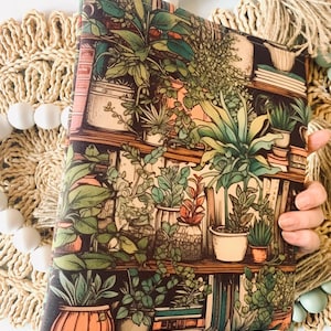 May include: A brown fabric pouch with a colorful print of potted plants and books on a shelf. The print features a variety of green plants in different pots, with some books visible on the shelves.