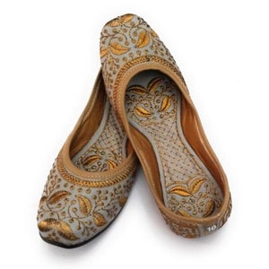K&ouml;nnte beinhalten: Ein Paar graue, bestickte flache Schuhe mit goldenen Blumenmustern. Die Schuhe haben eine spitze Zehenpartie und eine flache Sohle.