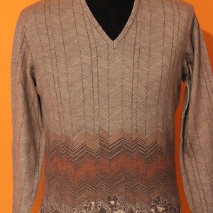 May include: A brown and beige sweater with a chevron pattern and a floral design at the bottom.