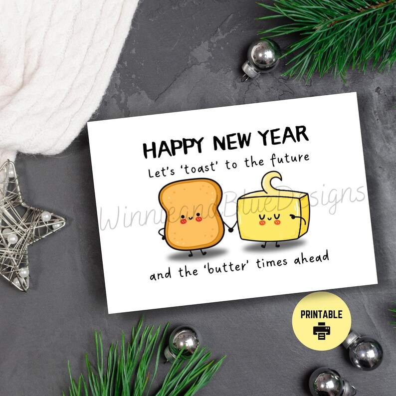 May include: A printable greeting card with a happy new year message. The card features a cartoon illustration of a slice of toast and a stick of butter holding hands. The text reads "Happy New Year. Let's 'toast' to the future and the 'butter' times ahead."