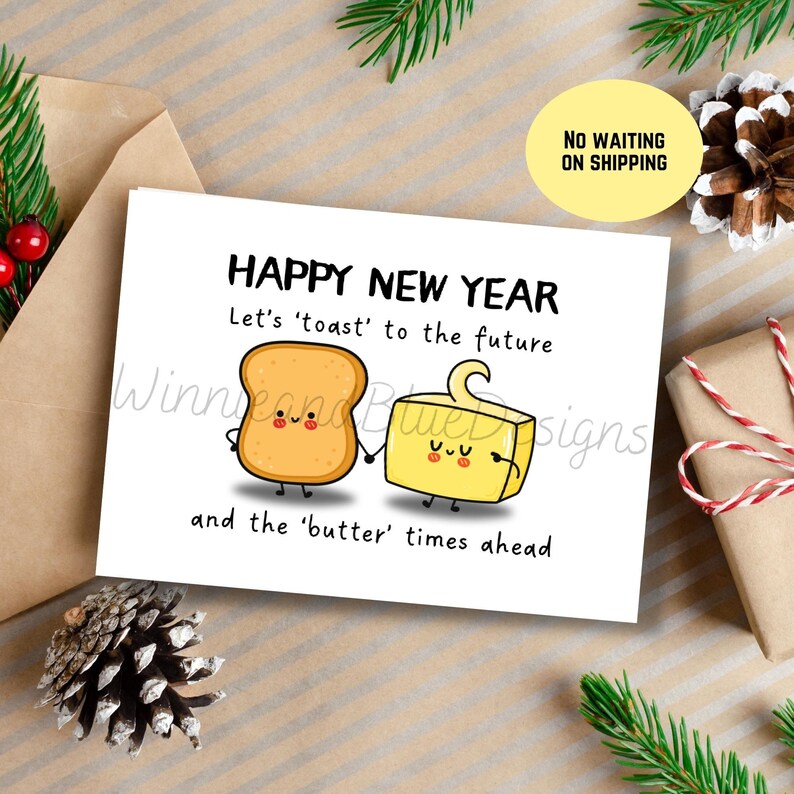 May include: A greeting card with a cartoon illustration of a slice of toast and a stick of butter holding hands. The text reads "Happy New Year. Let's 'toast' to the future and the 'butter' times ahead."