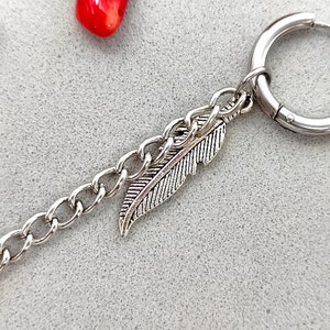 May include: Silver hoop earring with a silver chain and a feather charm.
