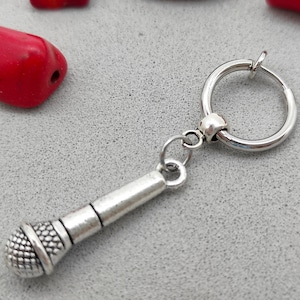 May include: Silver microphone charm attached to a silver hoop earring.