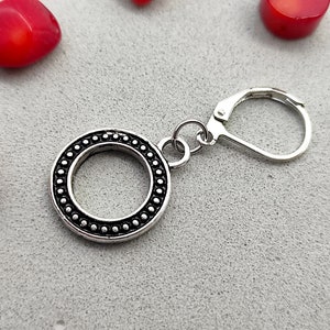Può includere: Orecchino d'argento con un design rotondo e perlato e una chiusura a gancio.