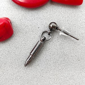 May include: A black bullet-shaped earring with a silver post and a clear rubber back.