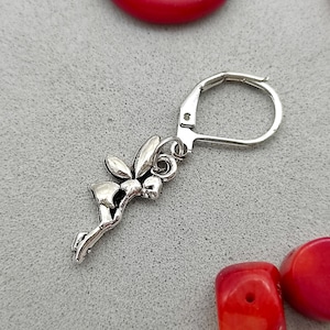 May include: Silver earring featuring a small fairy charm with wings outstretched. The earring has a lever back closure.