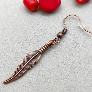 May include: A copper-coloured feather earring with a simple hook fastening.