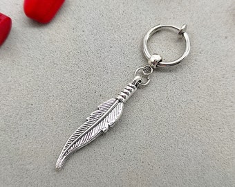 Könnte beinhalten: Silberner Federohrring mit einem Ringdesign. Der Ohrring ist aus Metall und hat eine silberne Oberfläche.