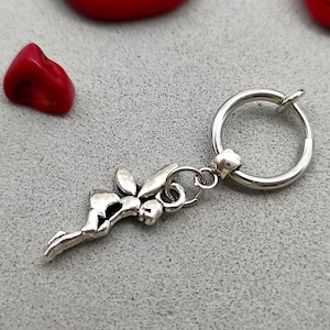 May include: A silver hoop earring with a dangling fairy charm. The fairy is silver and has wings and a flowing dress.