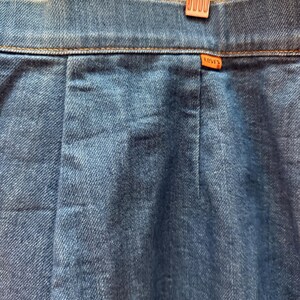May include: A close-up of the back waistband of a pair of blue denim jeans with a brown Levi's label.