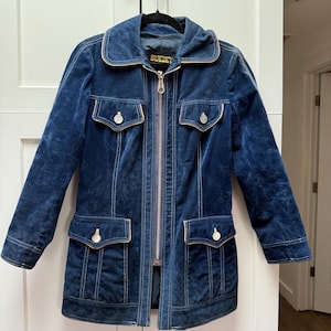 May include: A blue velvet jacket with a zipper closure and two flap pockets. The jacket has a white trim and the label "SUEDEY" is visible on the front.