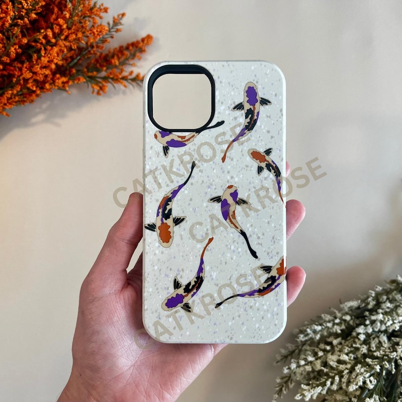 K&ouml;nnte beinhalten: Wei&szlig;e Handyh&uuml;lle mit glitzernder Oberfl&auml;che und einem Design aus bunten Koi-Fischen. Die H&uuml;lle hat einen Ausschnitt f&uuml;r die Kamera.
