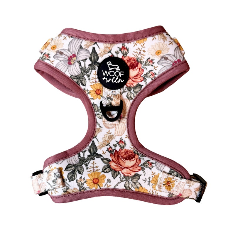 May include: A pink floral dog harness with a black label that says "Woof + Twin".