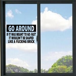 Peut inclure: Un autocollant de fenêtre rectangulaire avec le texte noir GO AROUND IF IT WAS MEANT TO GO FAST IT WOULDN'T BE SHAPED LIKE A FUCKING BRICK. Les mots GO AROUND sont en police blanche grasse sur fond noir, le reste du texte est en noir.