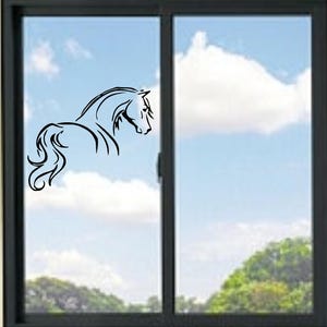 Peut inclure: Un autocollant noir représentant un cheval est appliqué sur une fenêtre. Le cheval est représenté de profil, avec une crinière et une queue fluides. Le fond montre un ciel bleu avec des nuages blancs et des arbres verts.