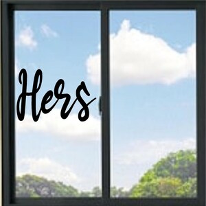 May include: A black vinyl decal applied to a glass window pane, featuring the word "Hers" written in a stylized, flowing cursive script. The lettering is opaque and positioned on the left side of the dark-framed sliding window unit.