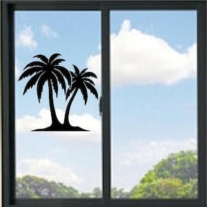 Può includere: Un adesivo in vinile nero raffigurante la sagoma di due palme che crescono da un piccolo cumulo di terra, applicato sul pannello sinistro di una finestra scorrevole con telaio scuro che si affaccia su un cielo azzurro con nuvole e alberi.