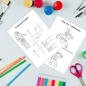 Puede incluir: Una hoja de trabajo imprimible en blanco y negro con dos ilustraciones de robots. Un robot est&aacute; en un crucigrama y el otro en un juego de 'Encuentra las 7 diferencias'. La hoja de trabajo est&aacute; rodeada de pintura de colores, pinceles, l&aacute;pices y tijeras.