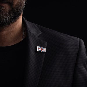 Op de afbeelding: Een man draagt een zwart colbert met een kleine speld met de Union Jack-vlag op de revers.