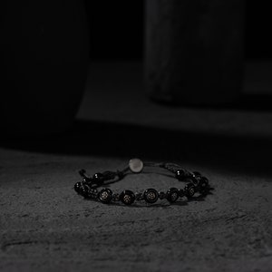 Black adjustable bracelet made of durable parachute cord, featuring matte hematite beads and a sterling silver slider for a custom fit.