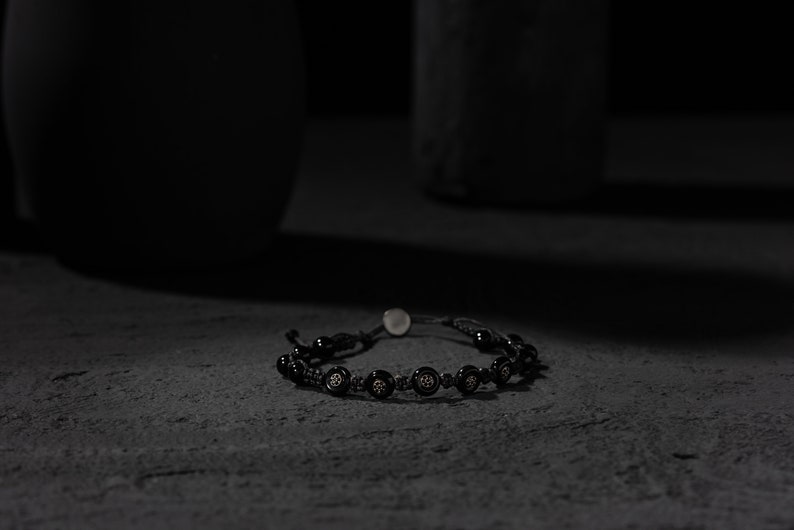 Black adjustable bracelet made of durable parachute cord, featuring matte hematite beads and a sterling silver slider for a custom fit.