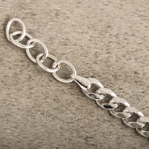 K&ouml;nnte beinhalten: Nahaufnahme einer silbernen Kettenkette mit einem Karabinerverschluss. Die Kette besteht aus dicken, ineinandergreifenden Gliedern.